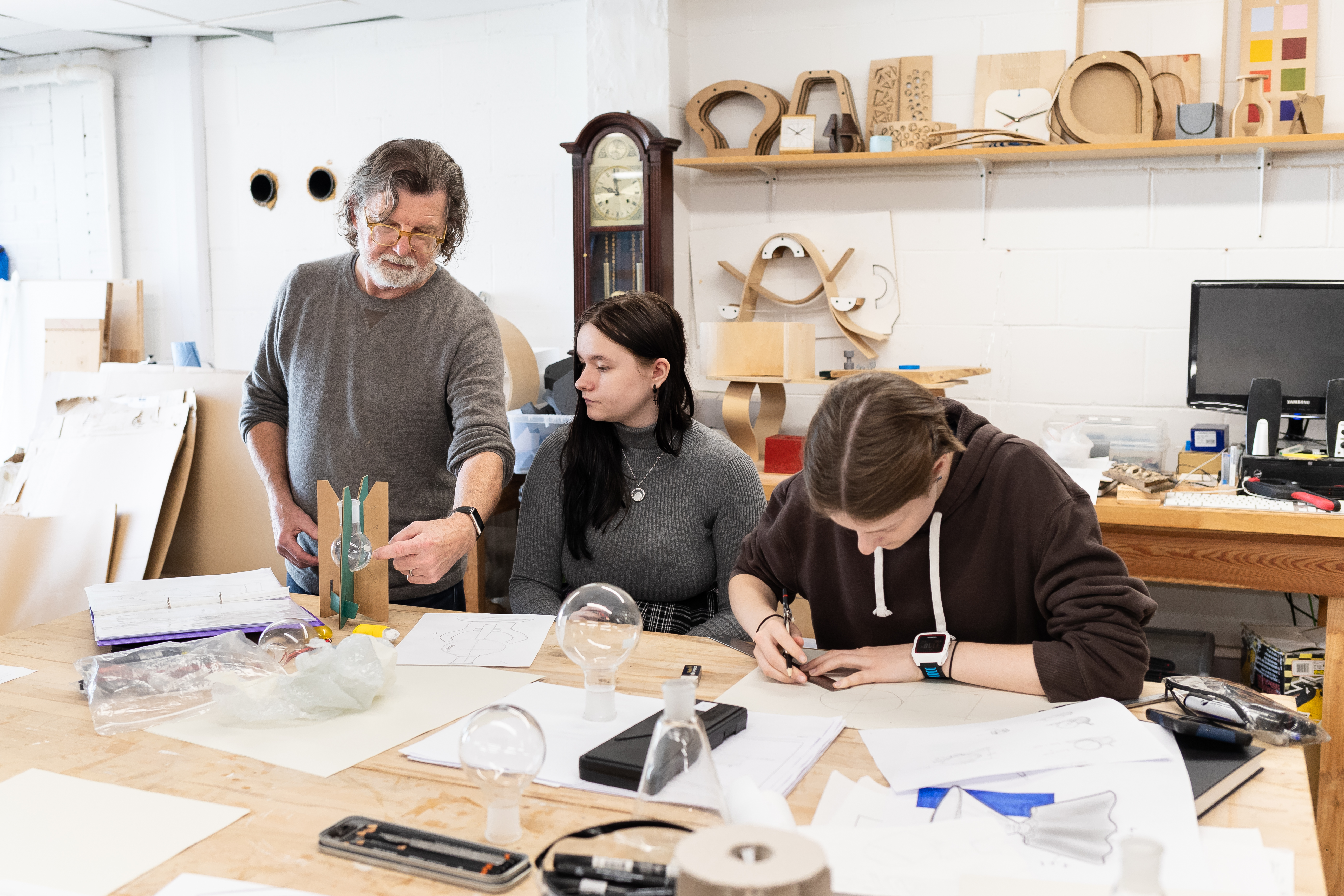 A lecturer teaching two students in a Product Design class