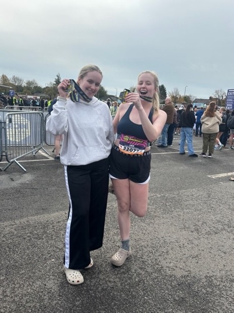 Chester Business School student Mali celebrating completing the 2024 Manchester half marathon with her twin sister.