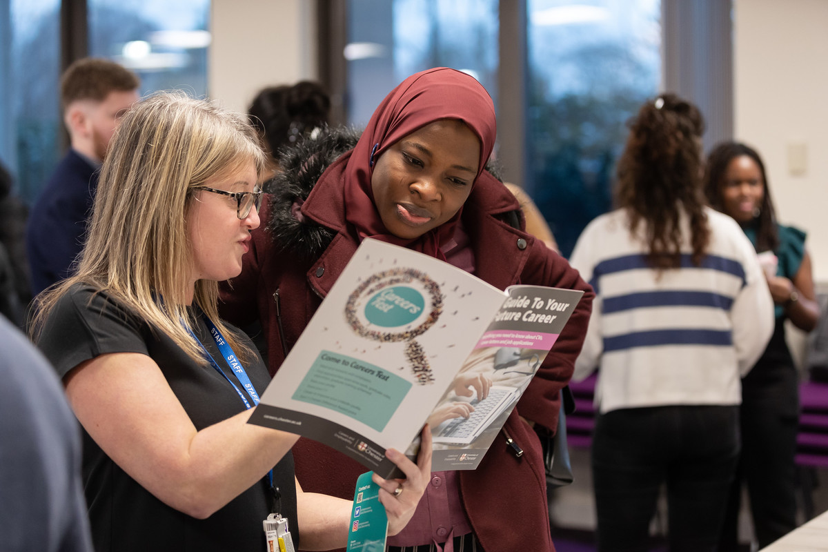 Student and staff looking at employability booklet