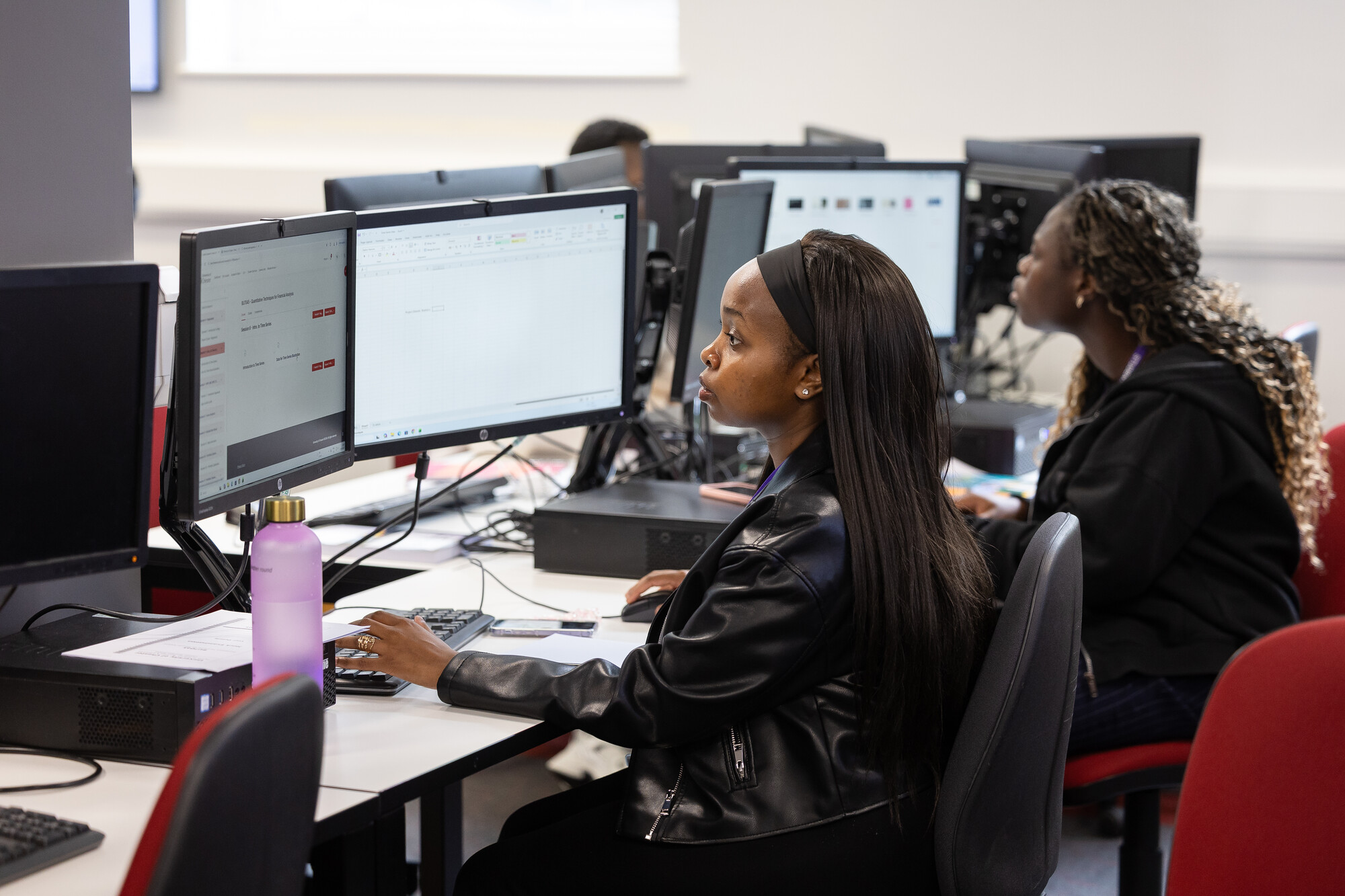 Two students sitting at computer screens in the Fintech Suite