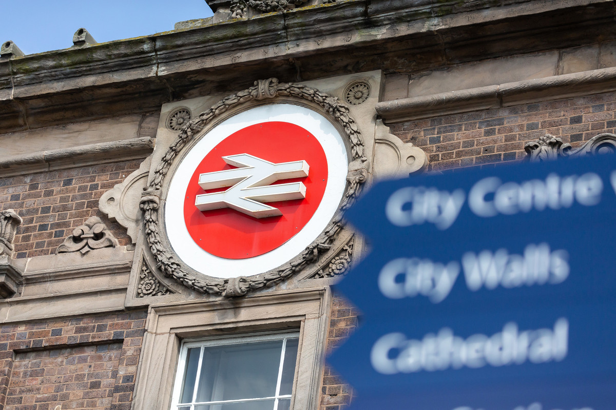 Chester train station sign in focus with chester landmark signposts, blurred in the forefront
