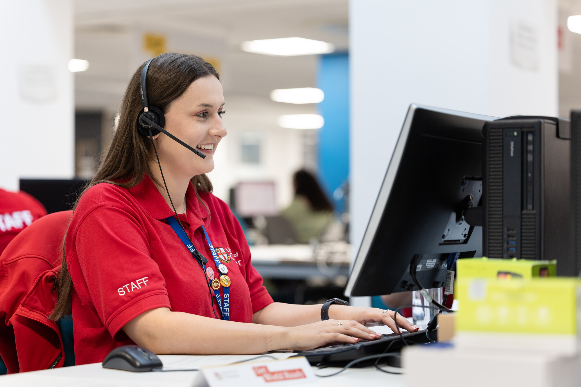 A member of staff wearing red Chester polo tshirt taking calls in a Clearing call centre