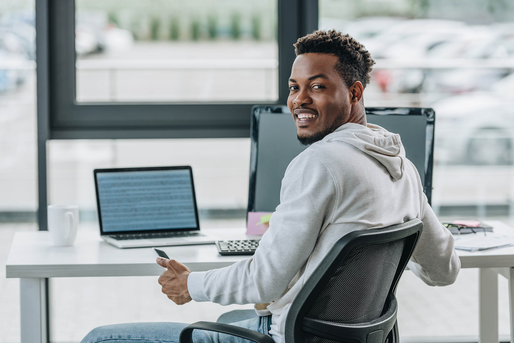 Happy programmer smiling at camera while sitting at workplace