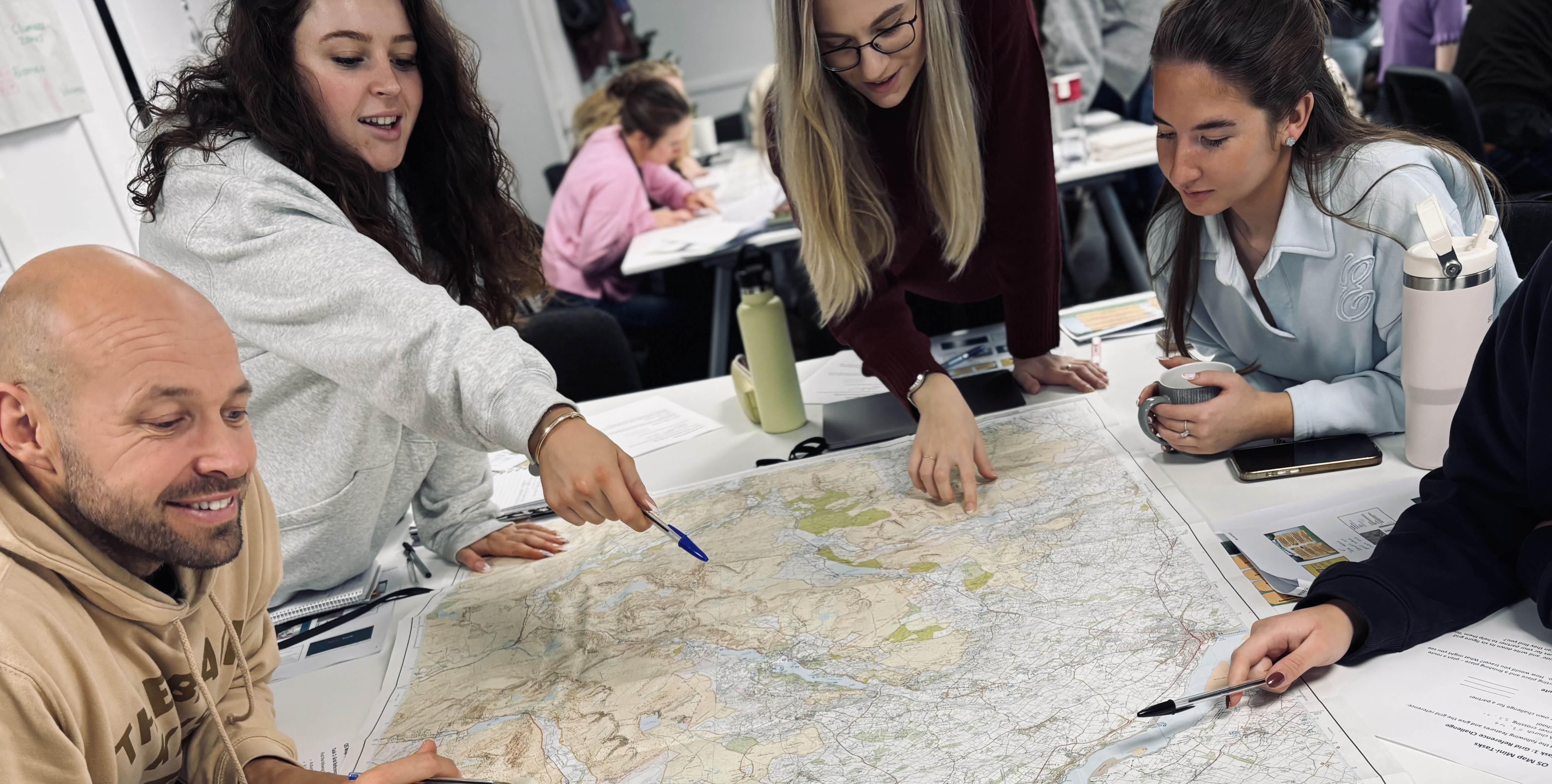 A diverse group of teachers gathered around a map, discussing directions and points of interest.