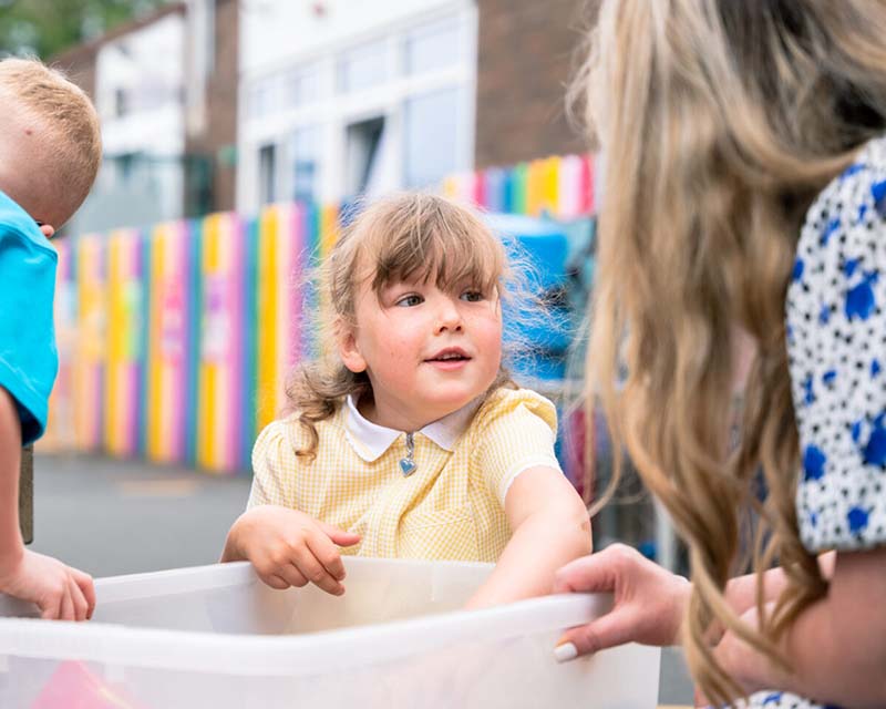 Children playing outdoor activities with teacher.