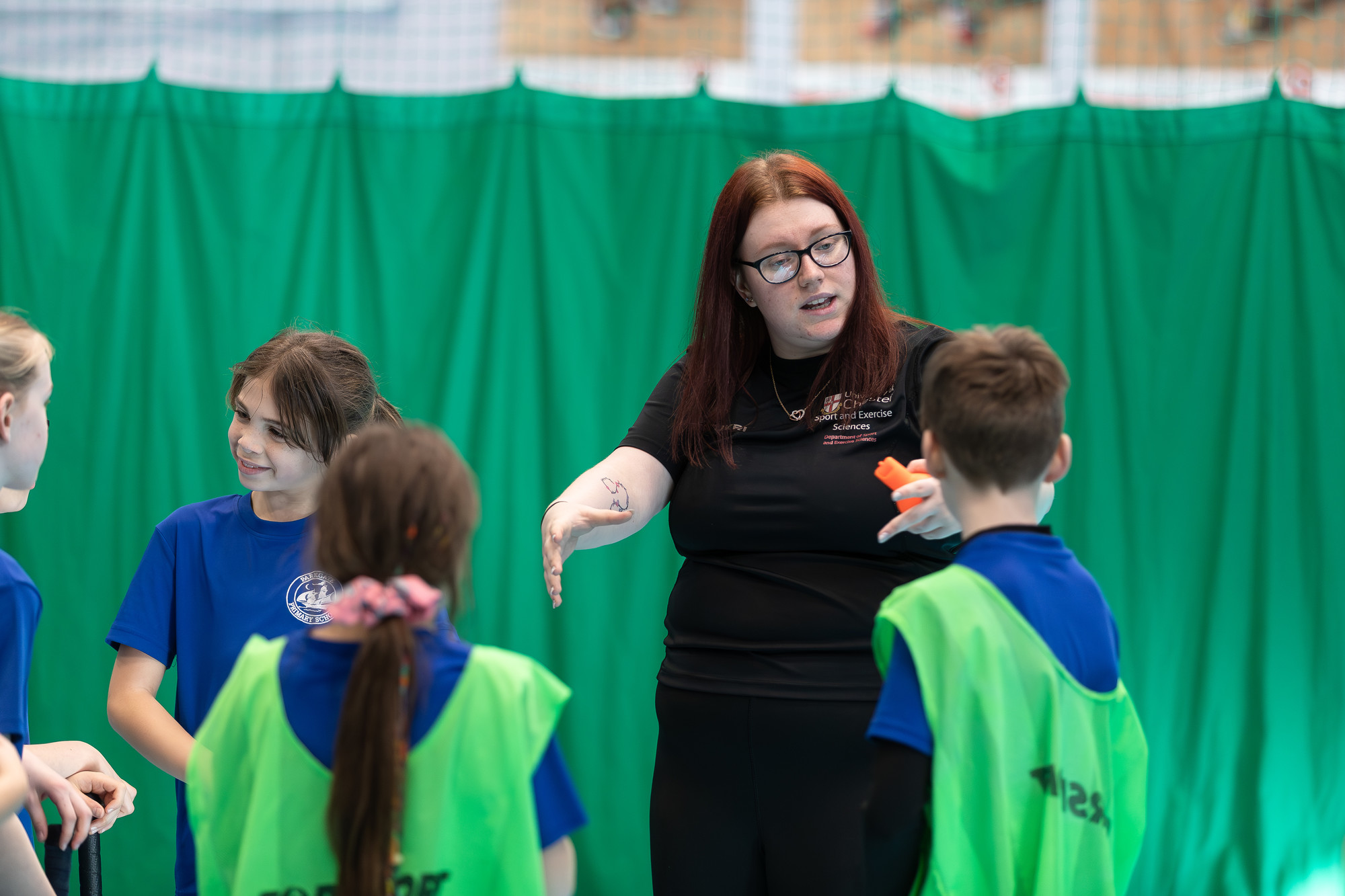 A female coaching primary school children in PE class.