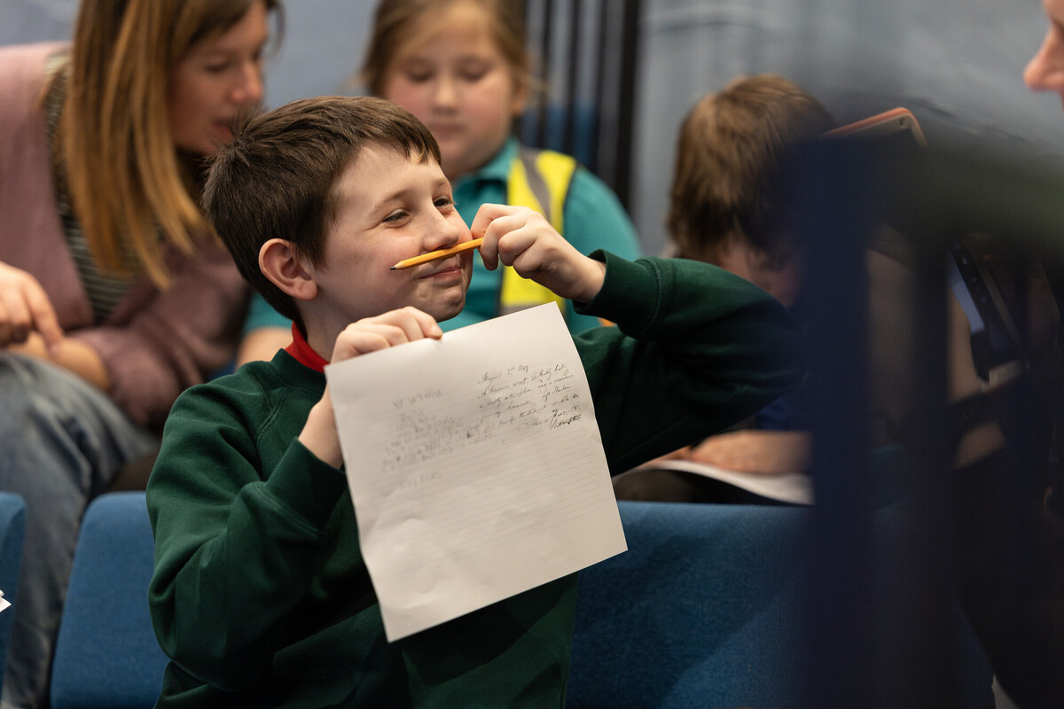 child holding up a pencil and paper
