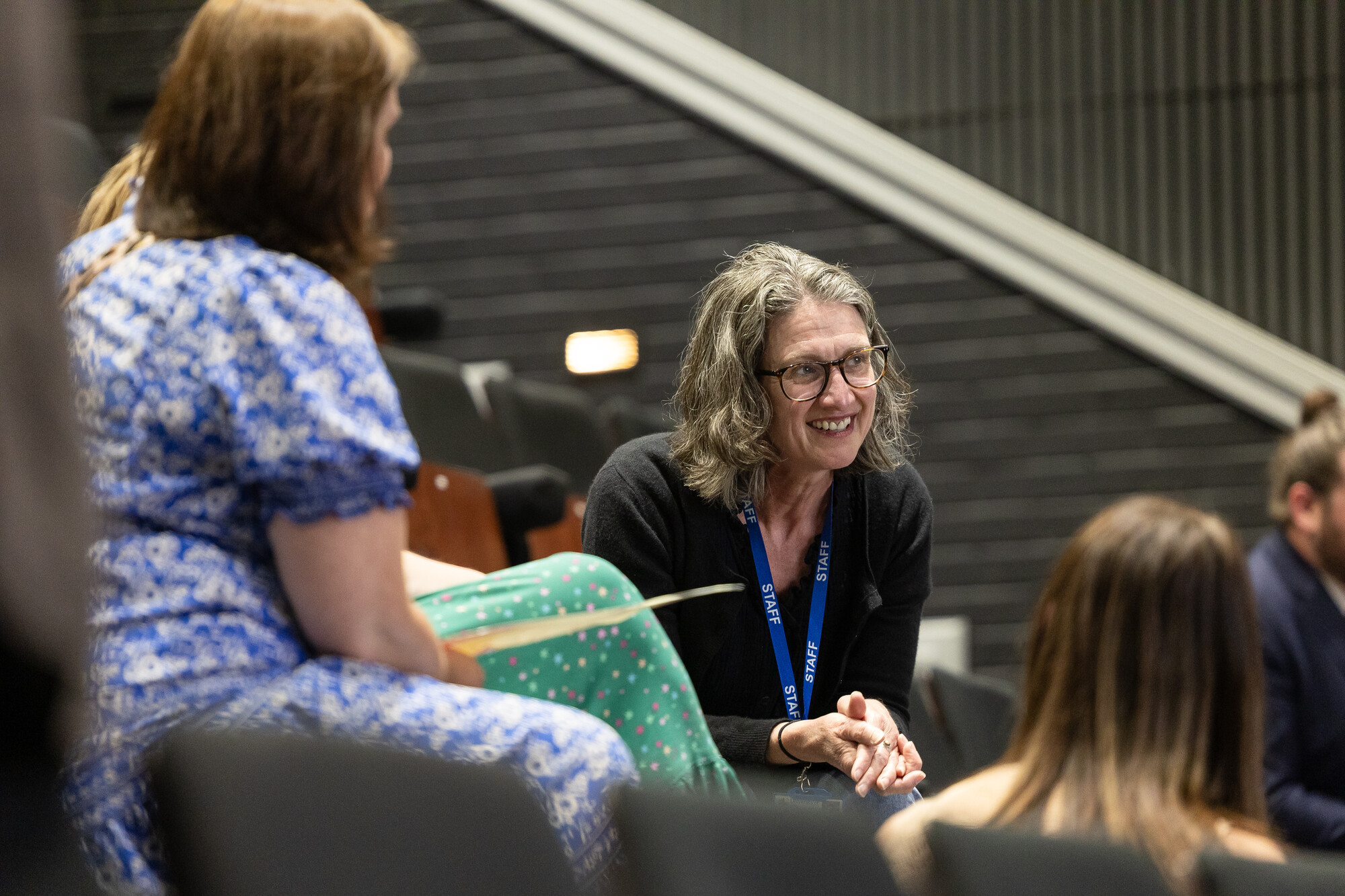 Prospective attendees speaking with a staff member in an auditorium setting during a campus event.