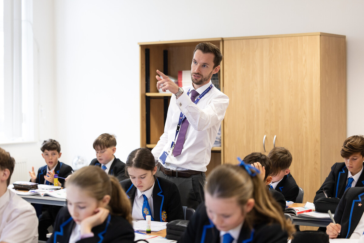 A student teacher instructs a group of attentive students in a classroom environment.
