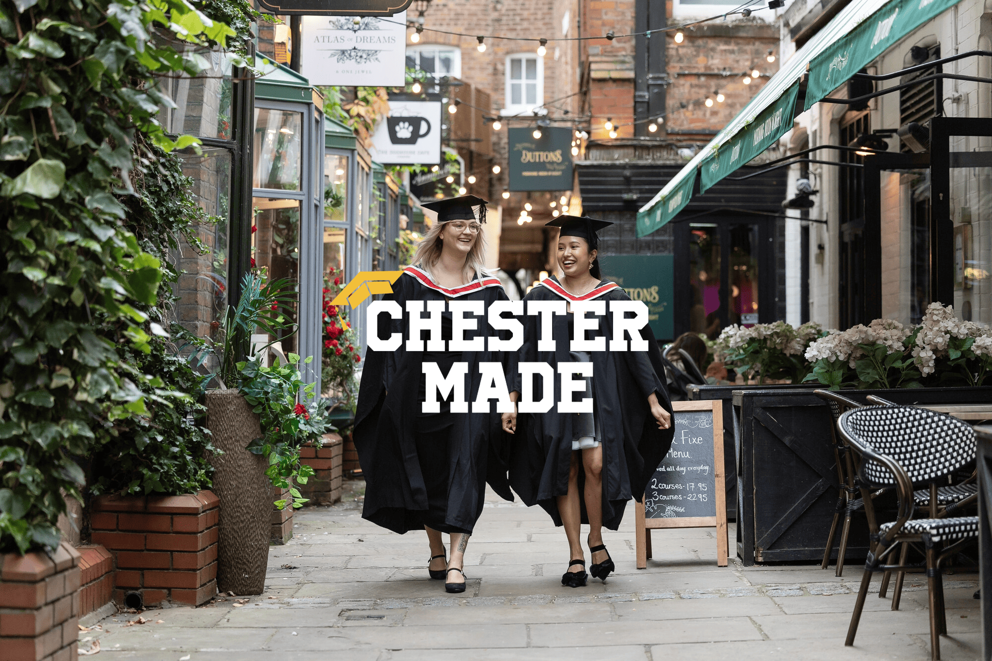 two female graduates walking through the streets of Chester wearing graduation caps and gowns