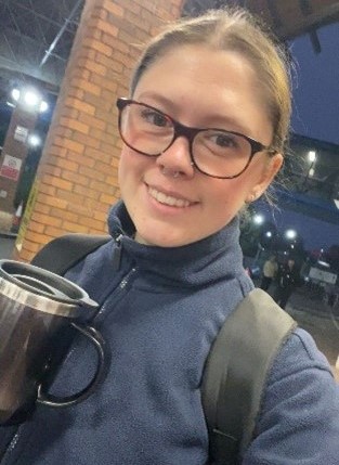 Megan smiling in a headshot while holding a flask