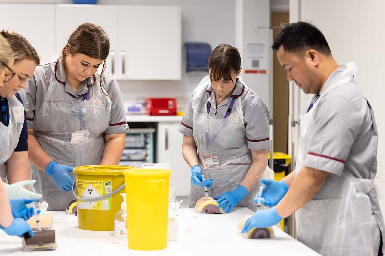 A group of nurses working together in ward simulation suite.