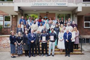 A group of people standing on steps with the University of Sanctuary award.