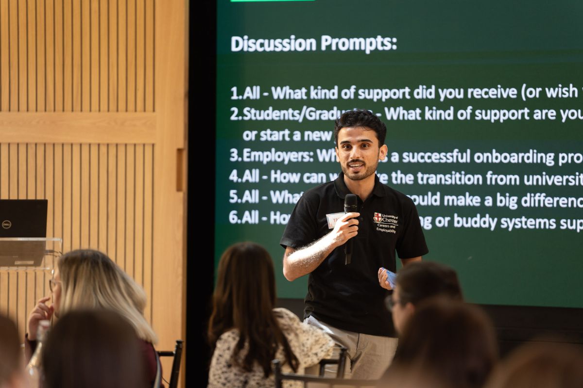A young man giving a presentation in front of a screen.