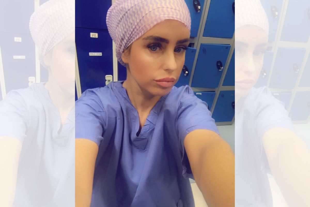 A selfie of a woman in nursing scrubs looking at the camera.