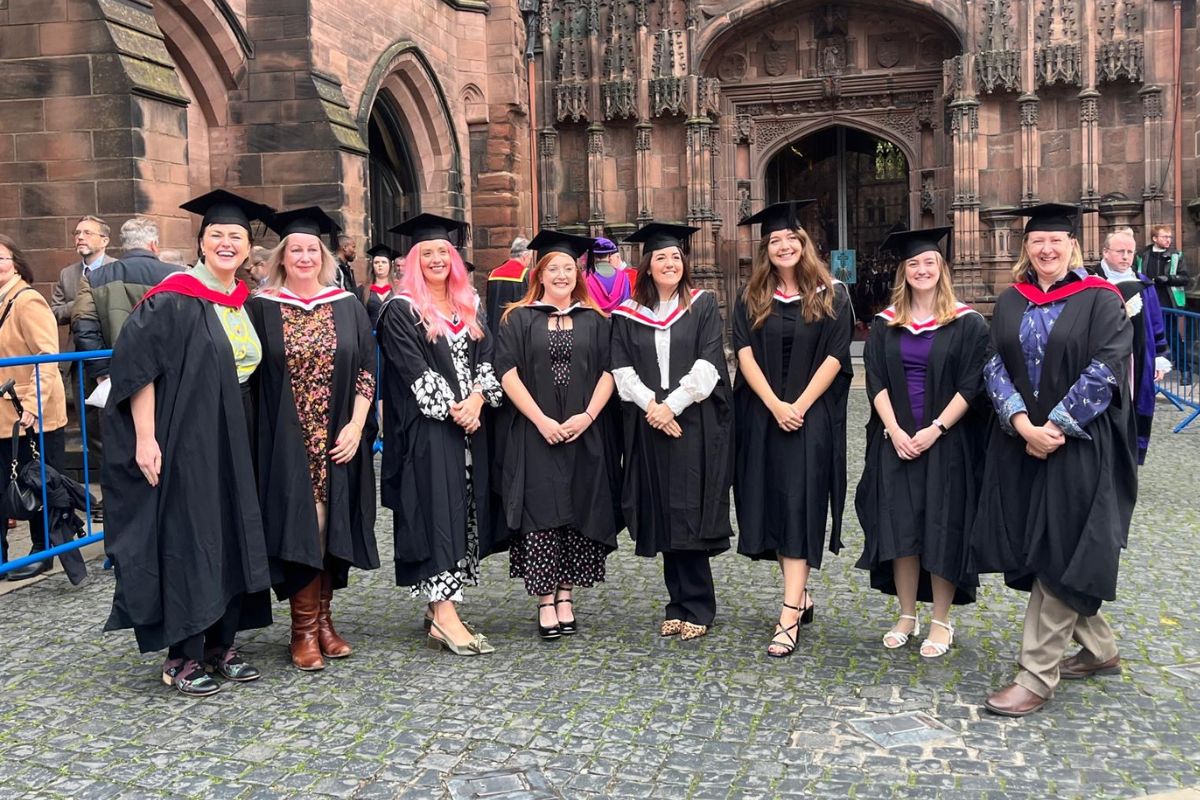 A group of women smiling at the camera, all wearing graduation gowns and caps.