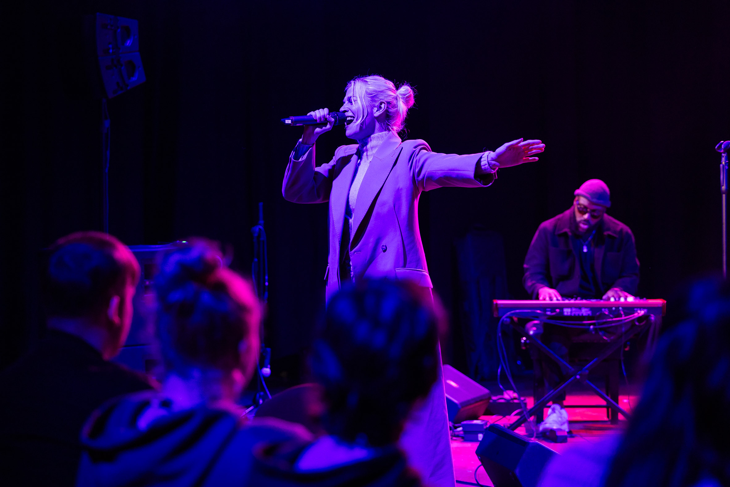 Pixie Lott standing and singing as she performs to students sat down.