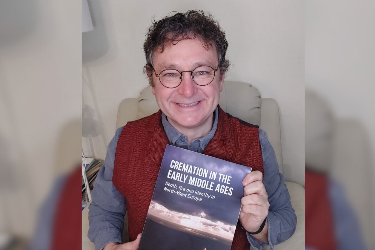 Professor Howard Williams with the publication.