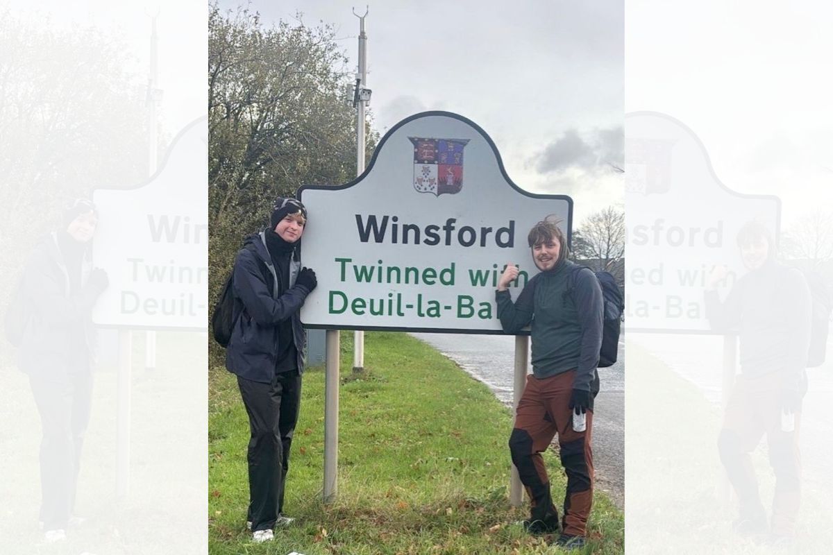 Two fundraisers stood by the welcome sign for Winsford.