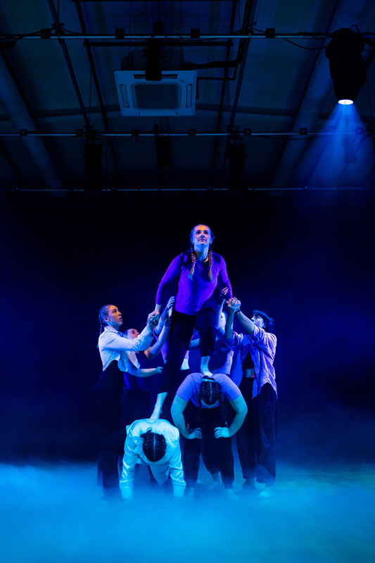 A group of dancers practices in a smoky, dimly lit room, emphasising their dedication to a dance degree course.