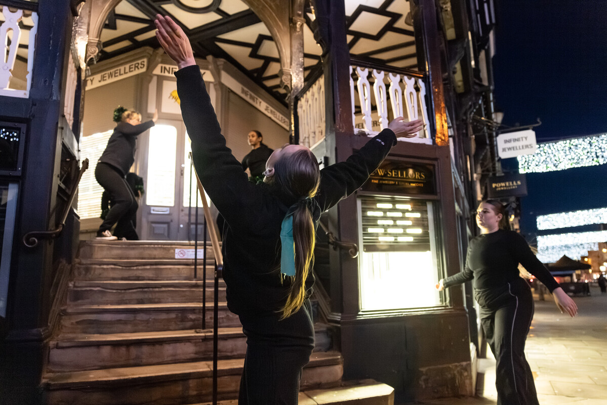 A woman dances gracefully on the steps of a building, showcasing her skills from her dance course and degree in dance.