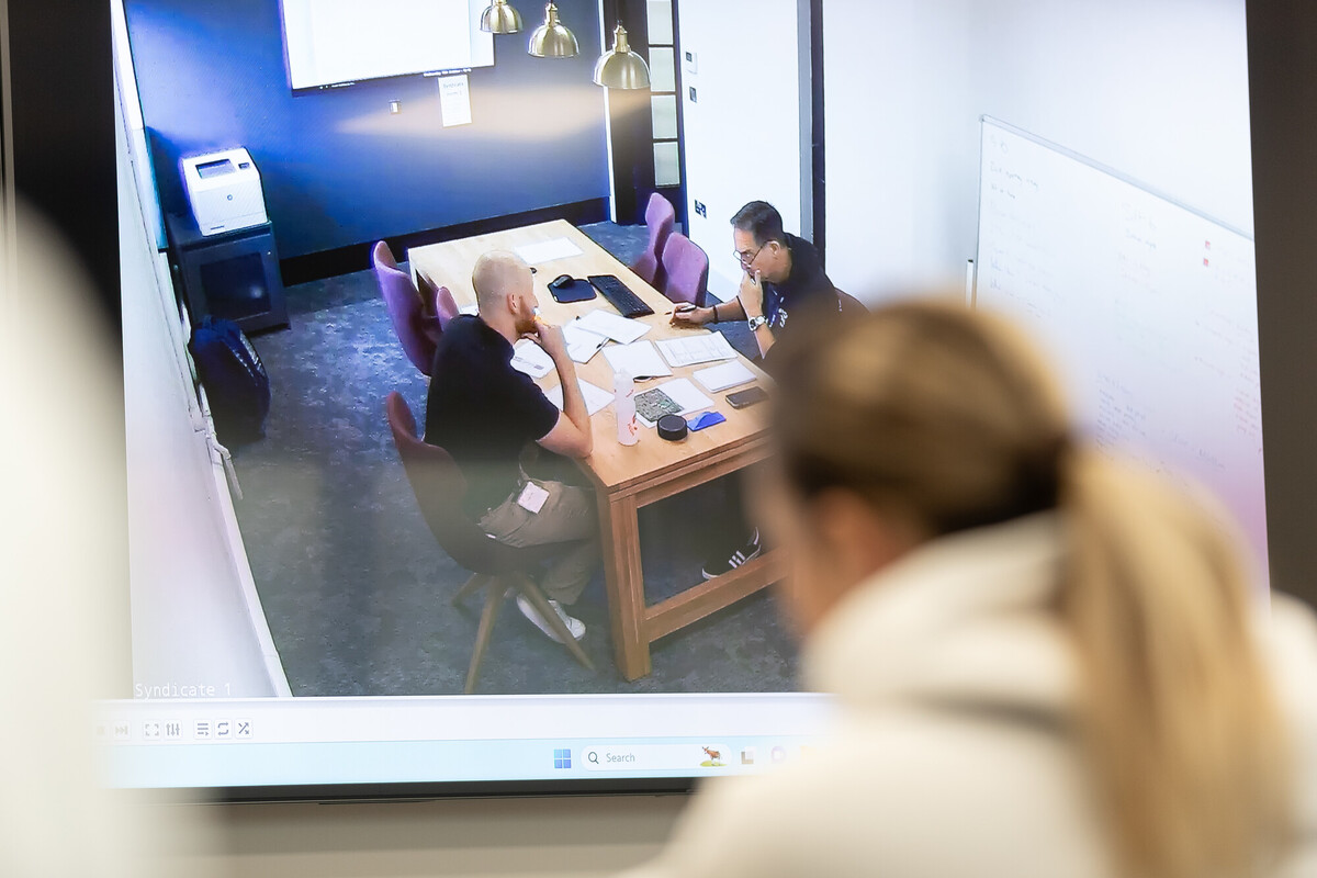 person examining two individuals on a screen sat at a table