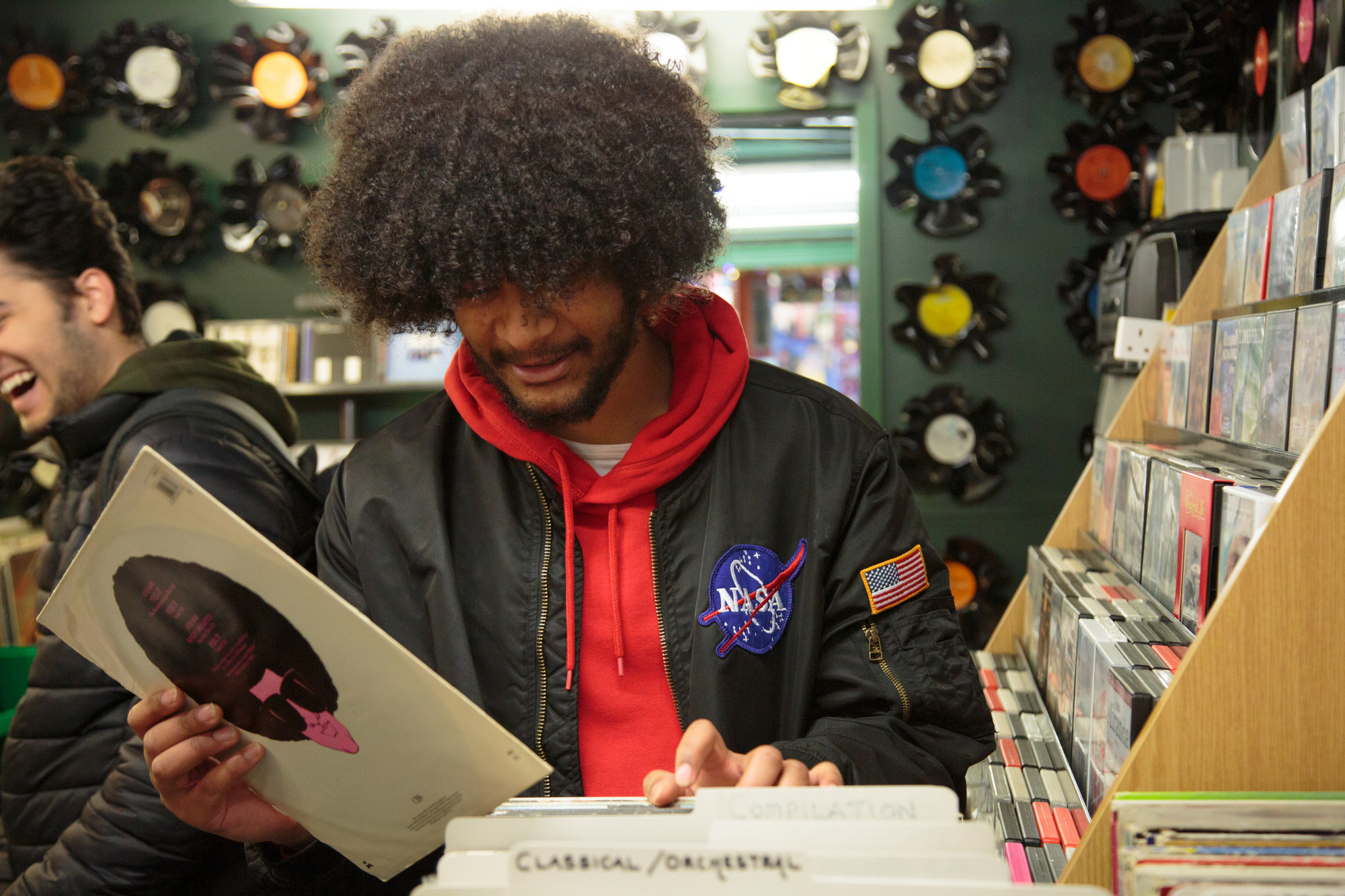 A student in a record shop, holding a vinyl record in one hand