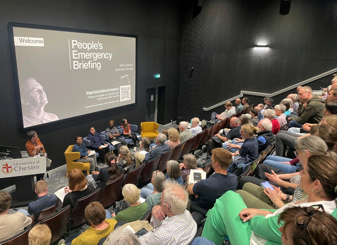 Audience members seated in a packed lecture theatre at the University of Chester attend a People’s Emergency Briefing event.
